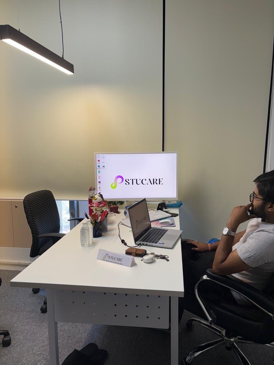 A workstation at the Stucare office, the monitor, laptop and desk nameplate all carrying the Stucare logo.